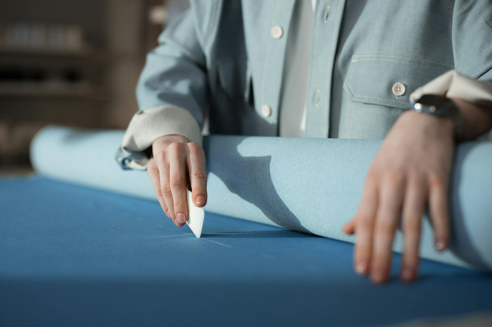 Home Tailors Hands Marking Blue Fabric With Chalk